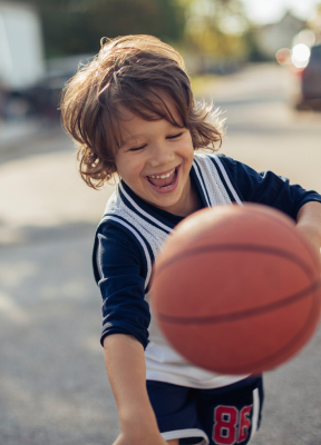 Little boy with healthy smile playing basketball after children's dentistry visit