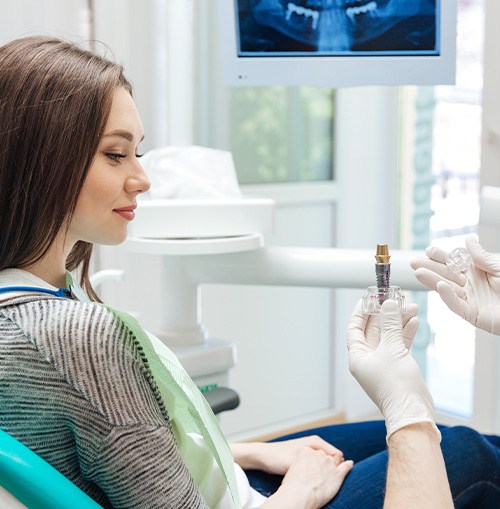 A dentist showing a dental implant to his female patient