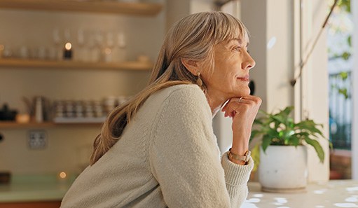 Senior woman smiling while looking out the window at home