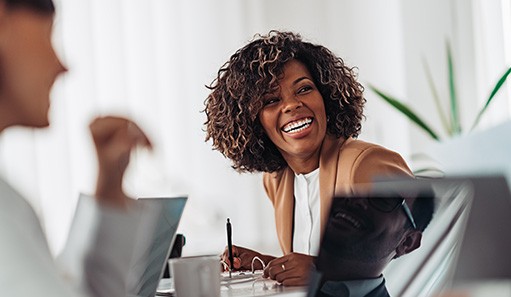 Woman smiling while taking notes during meeting