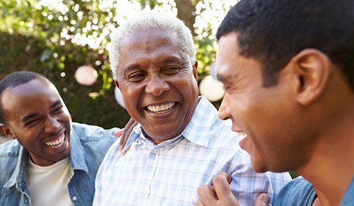 Smiling Oshkosh patient talking to sons to adjust to new dentures