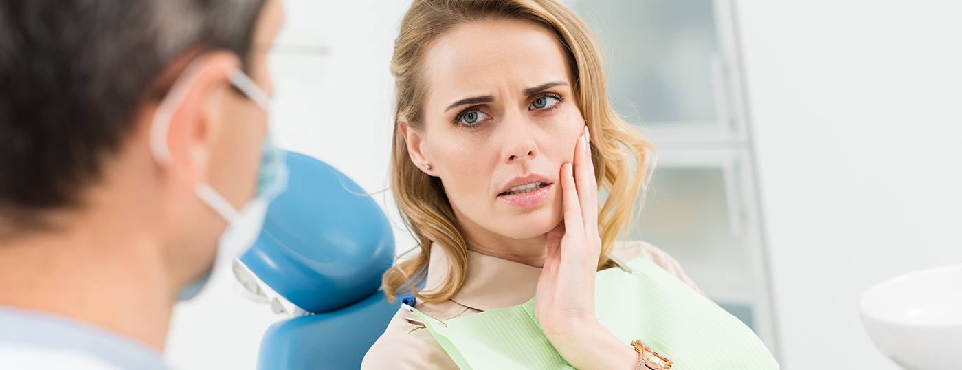 Woman holding cheek in pain during emergency dentistry visit