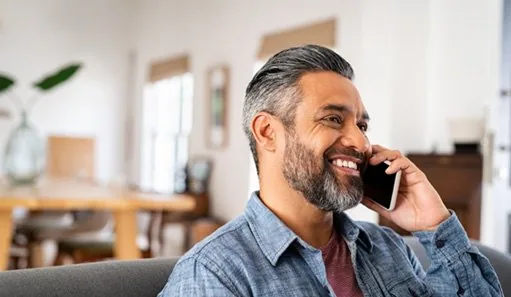 Man in blue shirt smiling while talking on phone