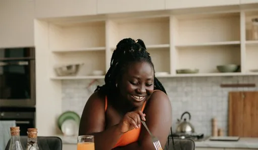 Woman smiling while eating healthy meal in kitchen at home