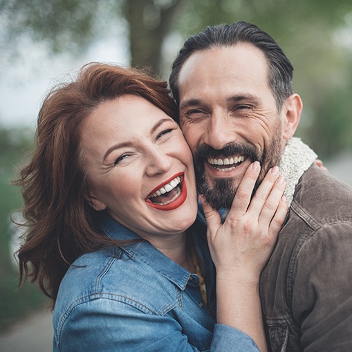 Man and woman smiling together after metal free dental crown restoration