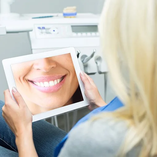 Womanlooking at virtual smile design on tablet computer