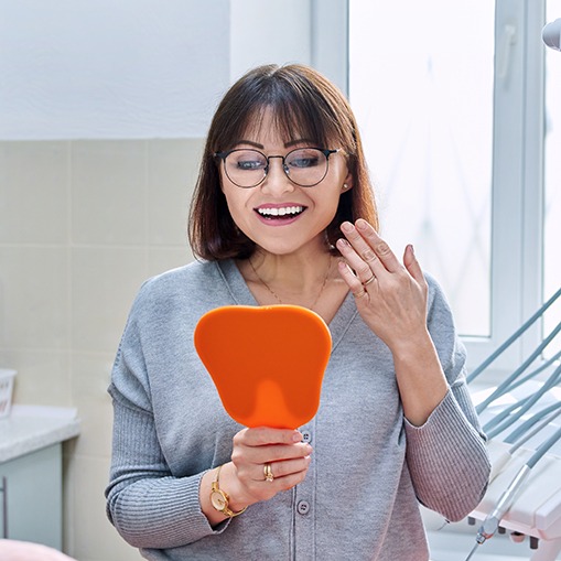 Woman at dentist’s office checking smile in mirror