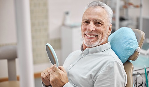 Senior male dental patient sitting in chair and smiling