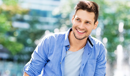 Man in button-up jacket walking outside and smiling