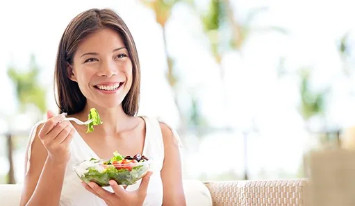 Woman sitting on couch eating a salad