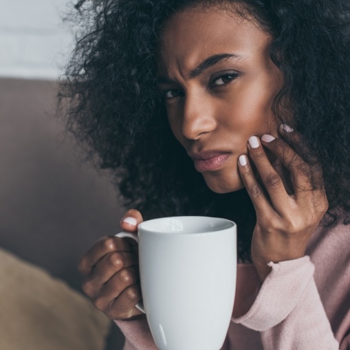 Woman in need of emergency dentistry holding cheek in pain