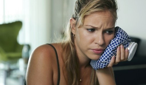 Woman with toothache holding ice pack to cheek