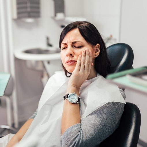 Woman holding cheek in pain during emergency dentistry visit