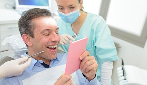 man looking at a mirror after working with an implant dentist in Oshkosh