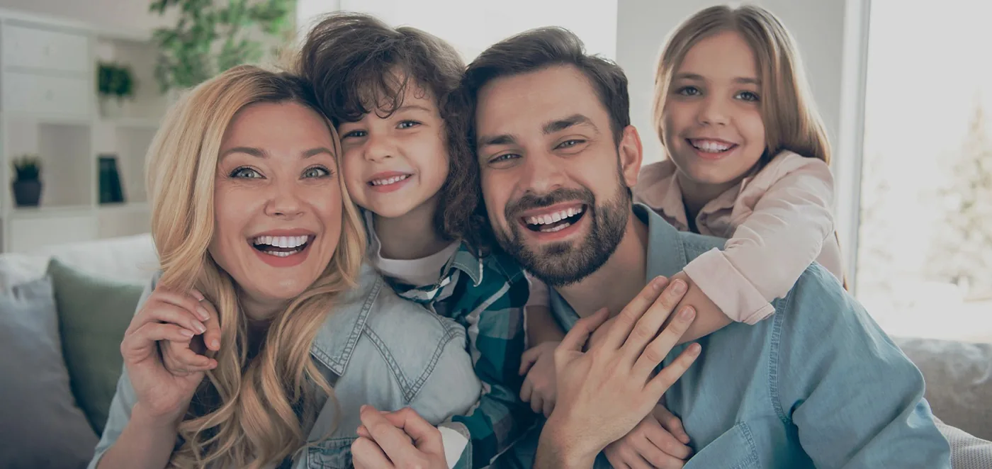 Family of four smiling after seeing their dentist in Oshkosh
