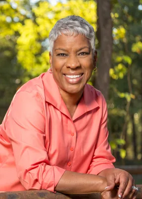 Woman in a peach colored blouse smiling outdoors