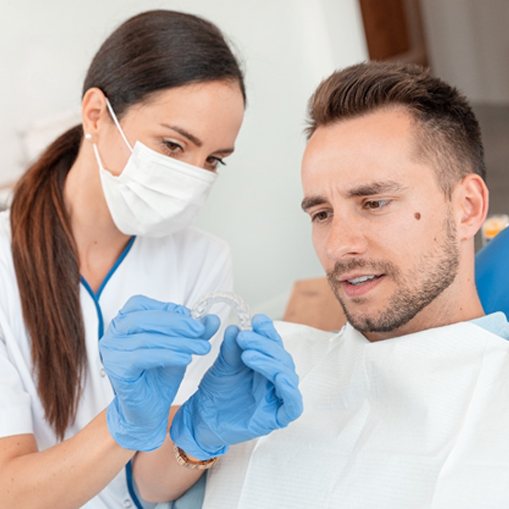 A dentist showing a male patient how a clear aligner works and discuss the cost of treatment
