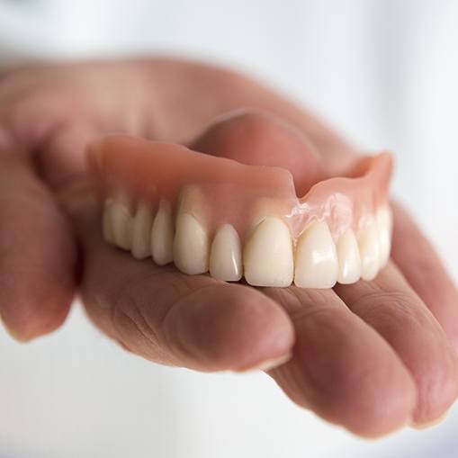 Hand holding a full denture