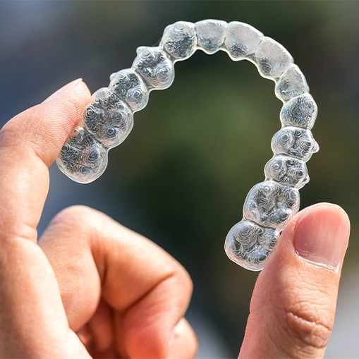 Hand holding an Invisalign tray