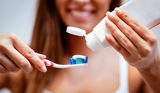 young woman putting toothpaste on toothbrush