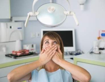 Fearful patient in need of sedation dentistry covering her mouth