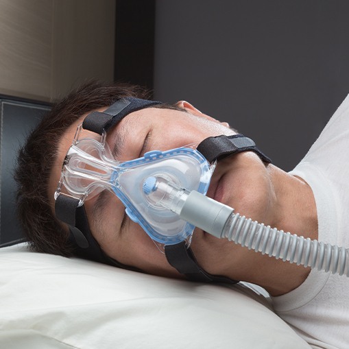 Man with C P A P nose mask in place sleeping