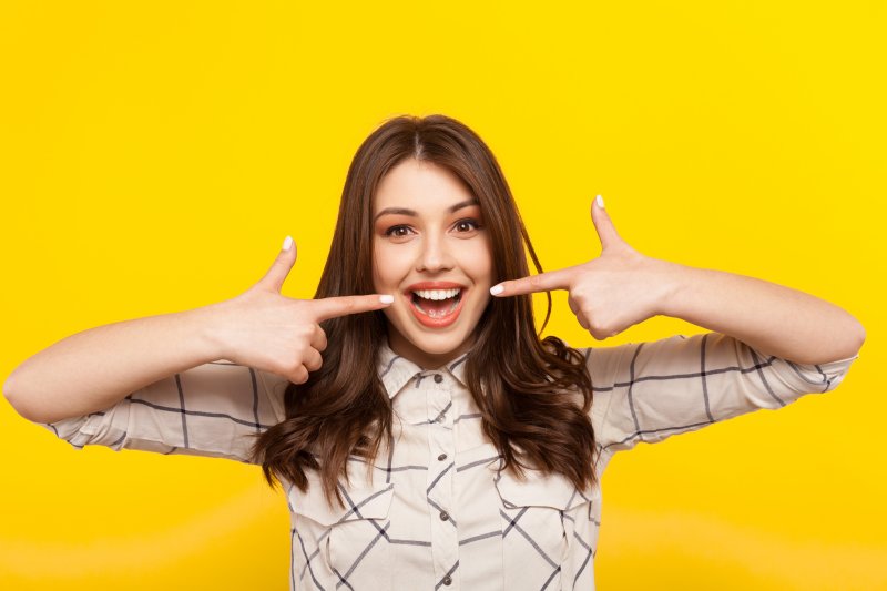 Woman smiling and pointing to her teeth