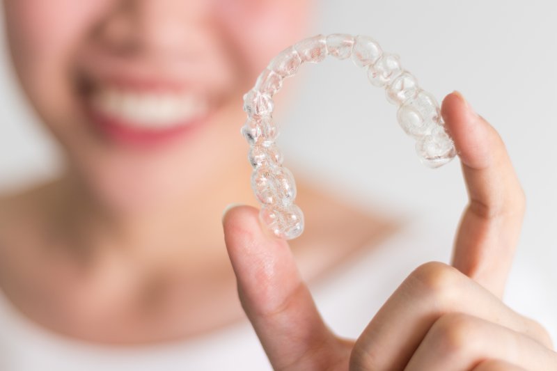 Woman holding up Invisalign clear aligner