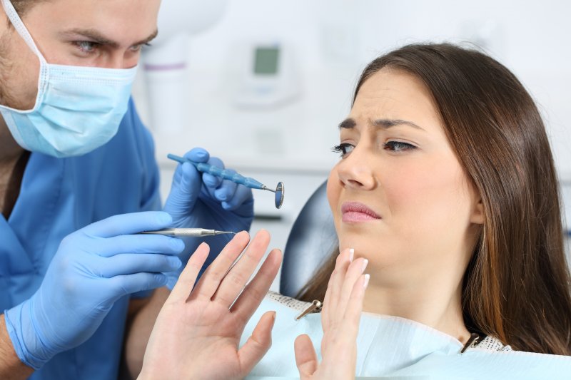 a young woman appearing fearful during a regular dental checkup and cleaning appointment 