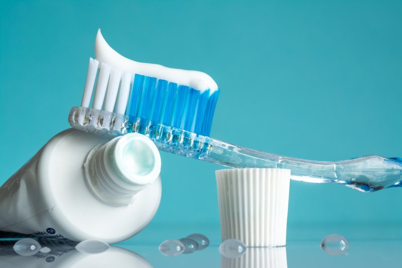 a toothpaste tube and manual toothbrush lying on a table 