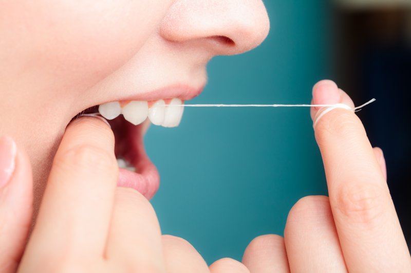 closeup of woman flossing her teeth