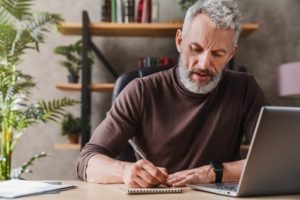 mature man writing on notepad 