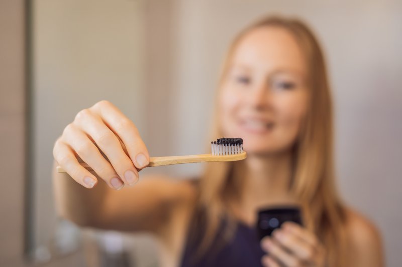 woman using activated charcoal to brush teeth in Oshkosh