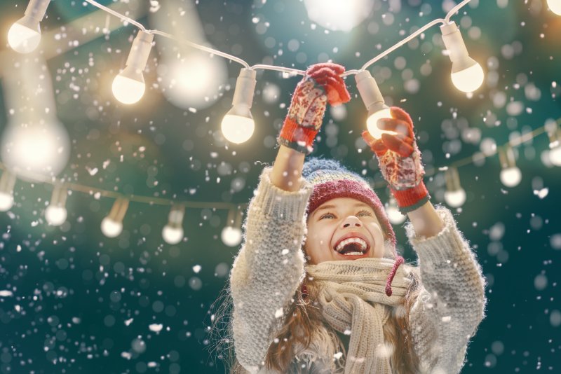 Young woman screwing in a lightbulb in the snow