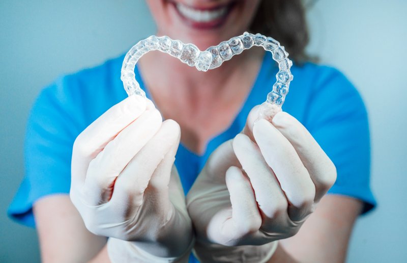 Dentist holding two Invisalign aligners in a heart shape