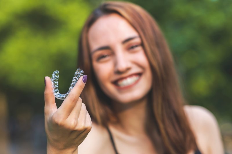 Young woman holding her Invisalign aligner