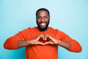 a man  smiling and using her hands to form a heart