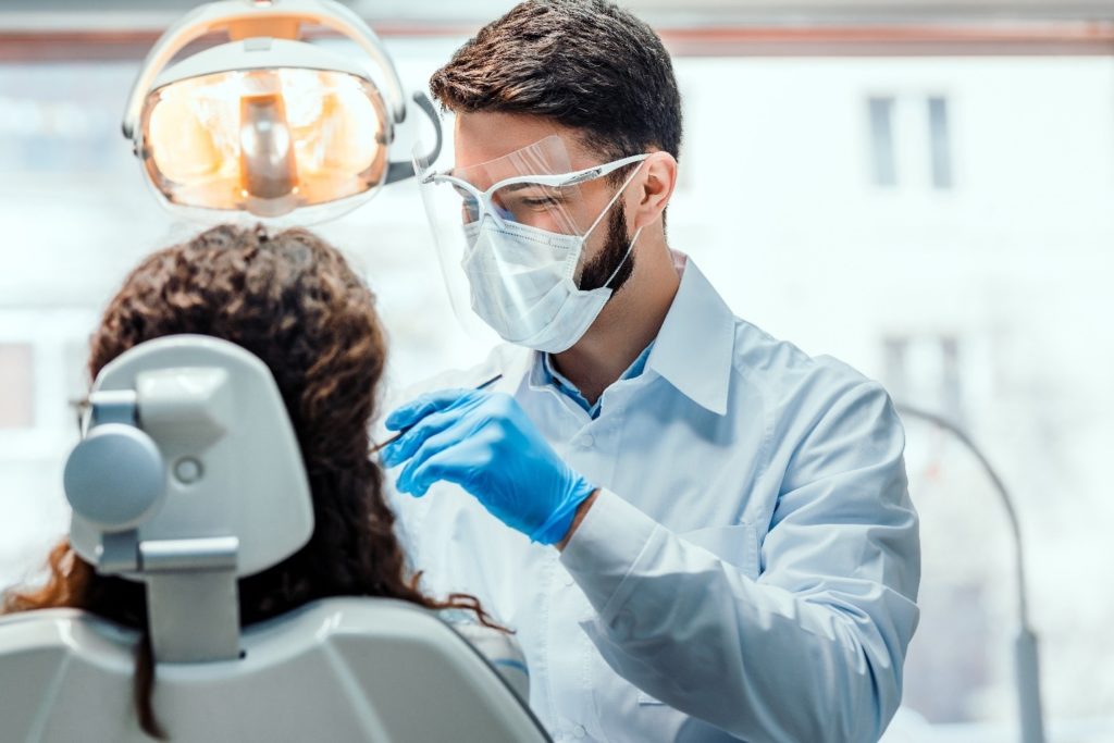 dentist performing oral cancer screening on patient