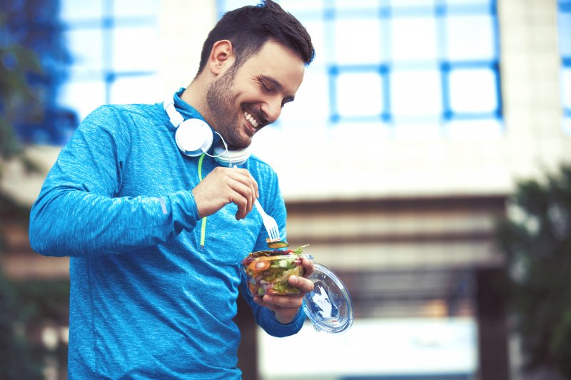 Man smiling and eating salad after exercise
