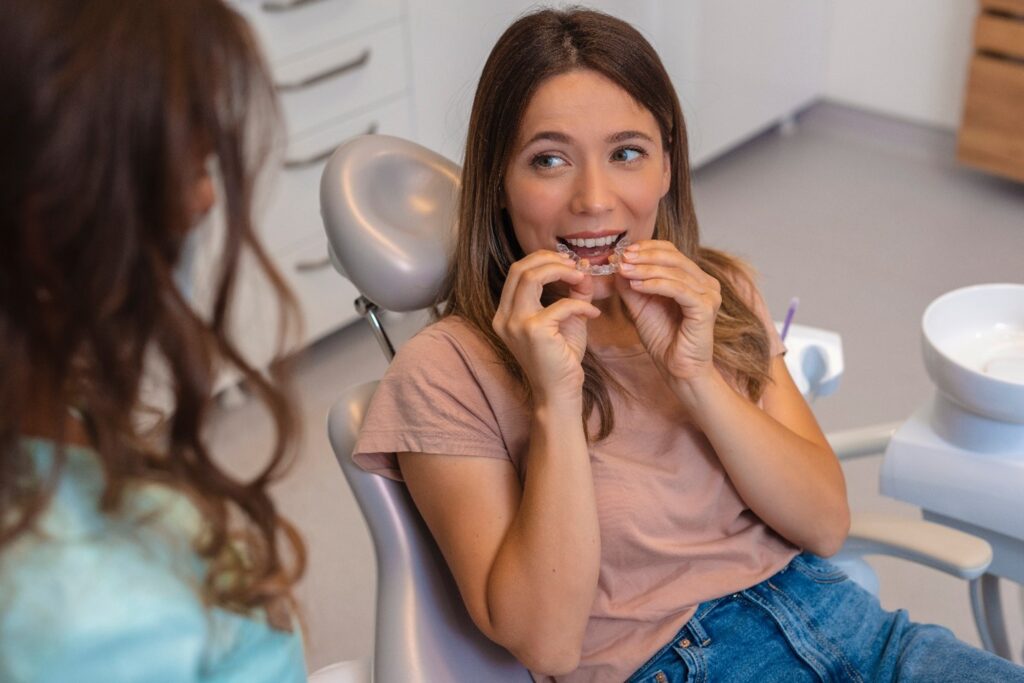 Patient smiling at dentist while putting on clear aligner
