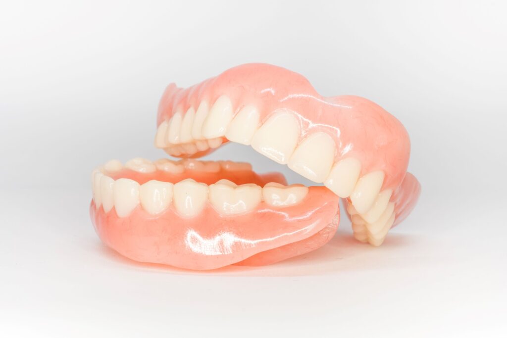 Upper arch of dentures resting on lower arch of dentures with white background